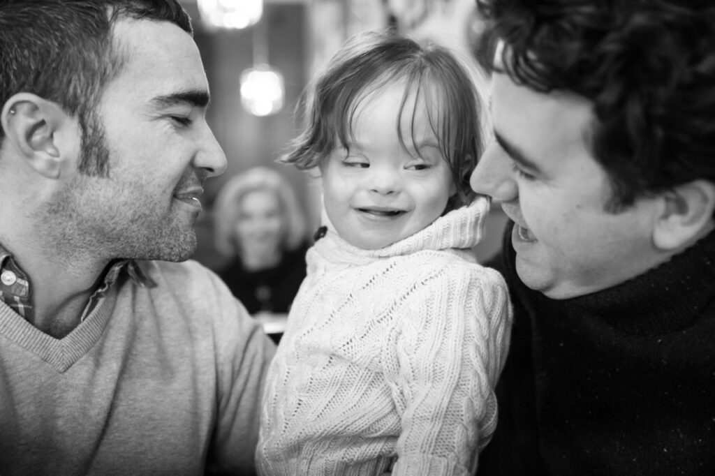 dads cuddling with toddler son at a diner restaurant during a day in the life family photo session