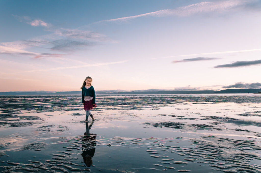 Young toddler girl wading in the shallow water at Alameda Crown Beach.