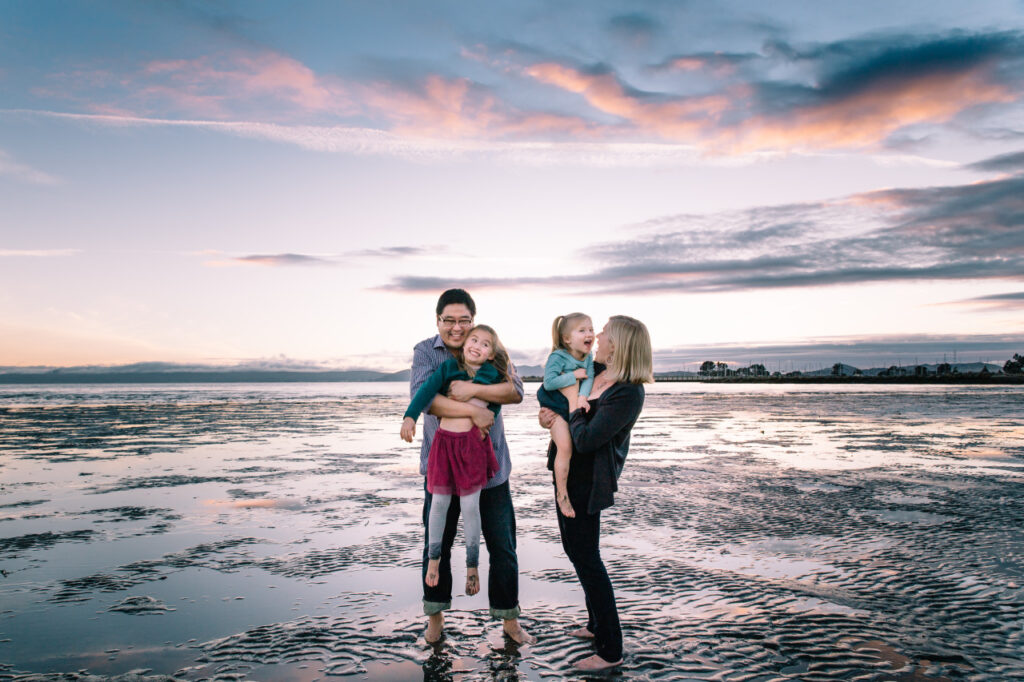 Family holding each other and making goofy faces during low tide at Alameda Crown Beach.
