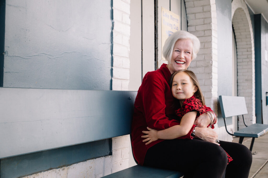 Grandmother and granddaughter hugging on a bench at Lake Merritt in Oakland.
