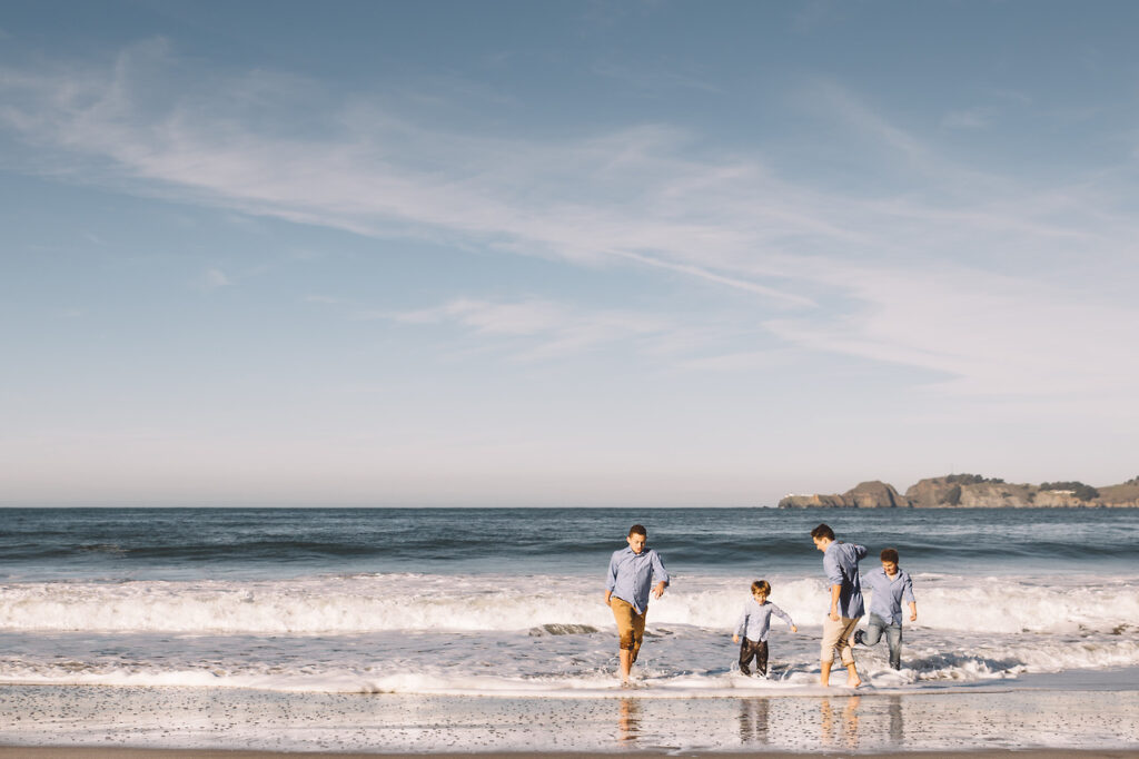boys jumping the waves at baker beach in san francisco.