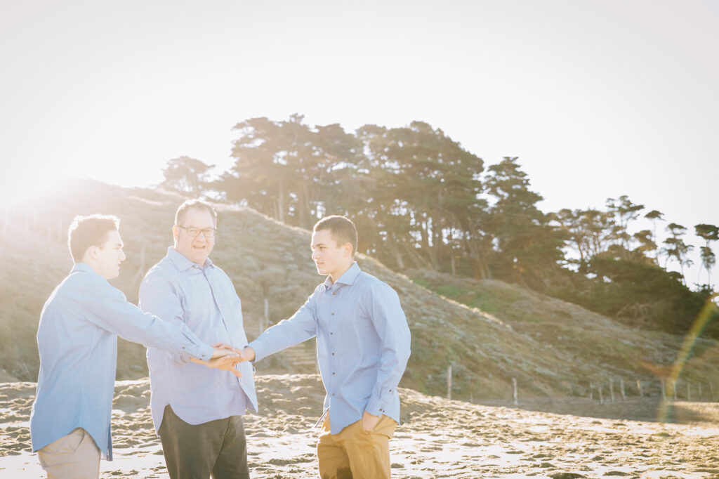 dad and teenage boys doing high fives at baker beach.