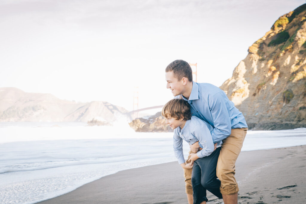 sibling brothers hugging at baker beach during a family photo session.
