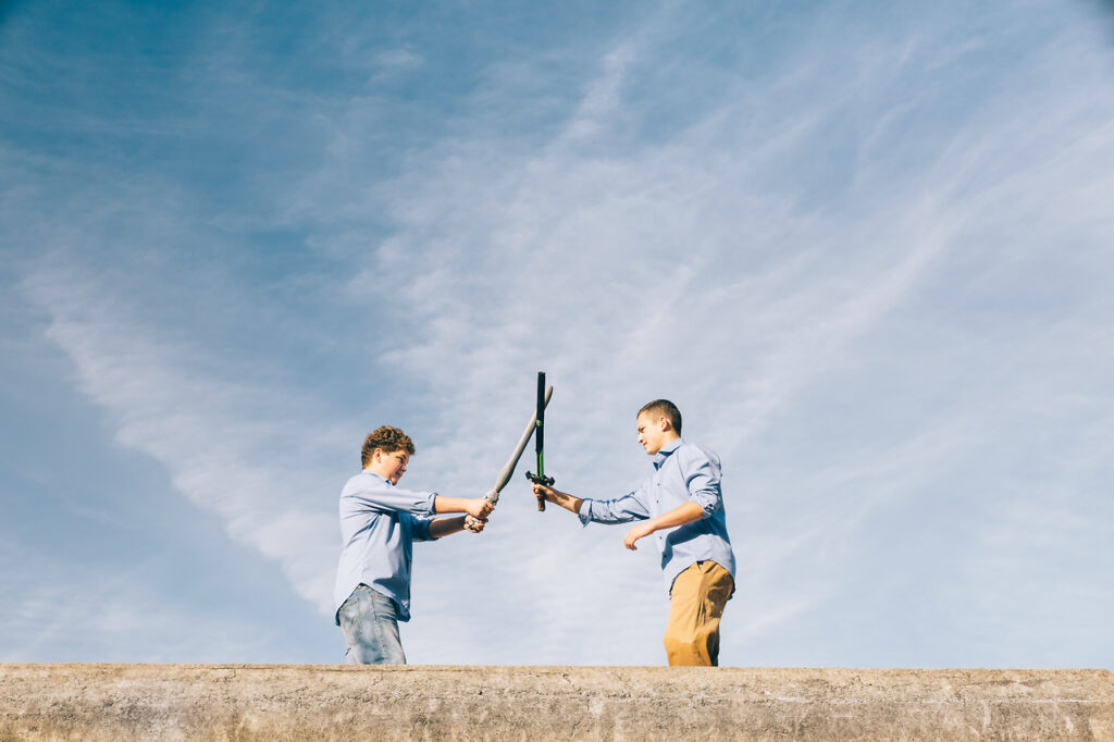 teenage boys spearing with toy swords at battery chamberlin in san francisco.