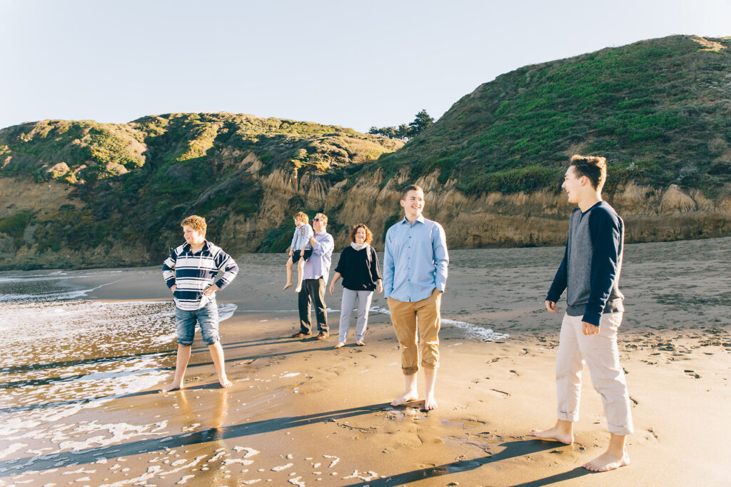 family with teenage boys wading in the water at baker beach.