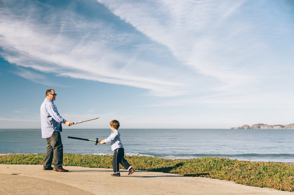 dad and young son playing with toy swords at battery chamberlin in san francisco.