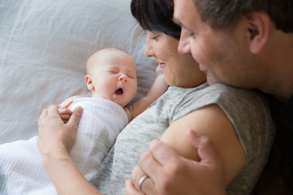 baby boy yawns with mom and dad gazing adoringly family home session sf bay area