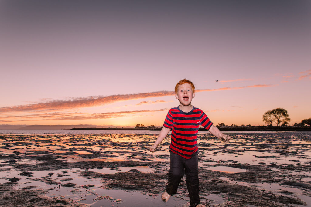 san-francisco-family-photographer-carmen-dunham-photography-KP6 boy laughing and running through mud at beach during low tide at sunset family session crab cove sf east bay area