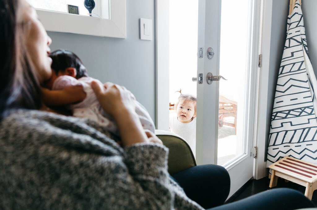 big girl sibling checking on baby sister newborn home session sf bay area