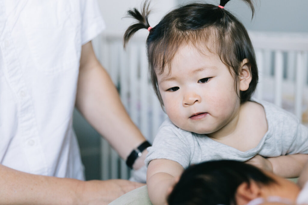 big girl sibling holding baby sister's head newborn home session sf bay area