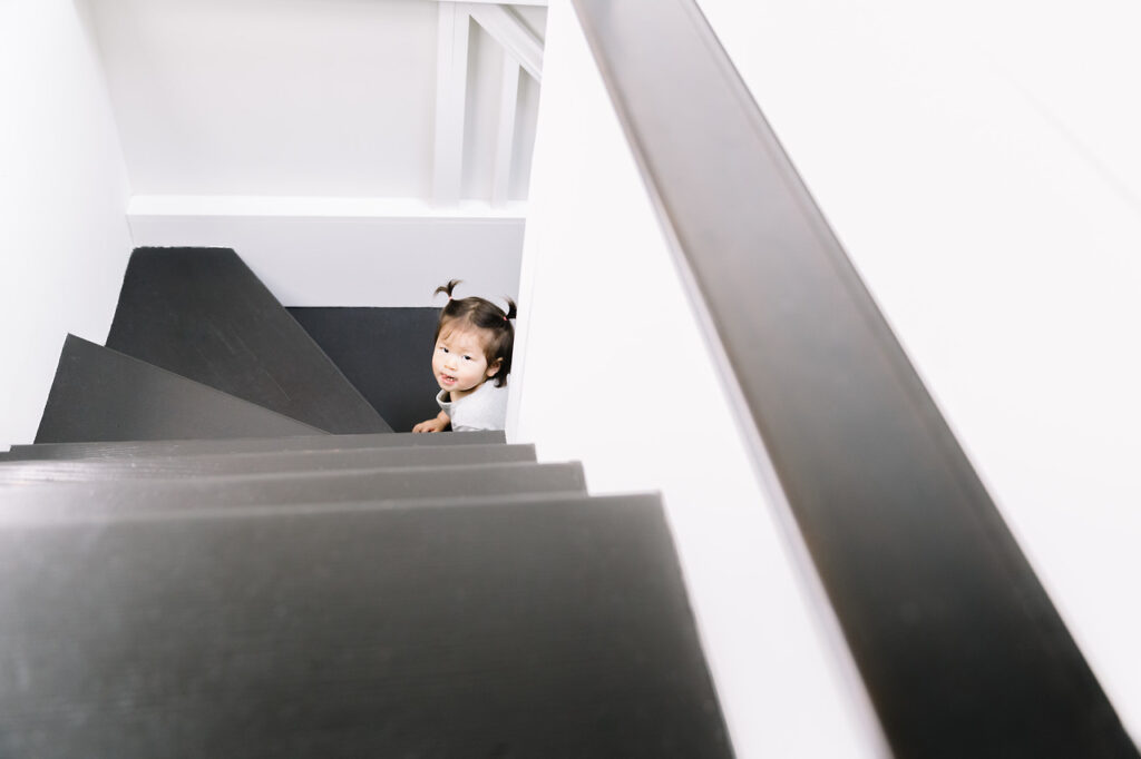 big sister sibling climbing up stairs newborn home session sf bay area
