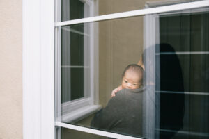 baby boy being carried near window newborn home session sf bay area