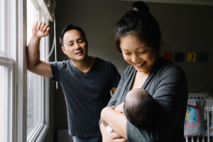 mom holding son with dad admiring from behind newborn home session sf bay area