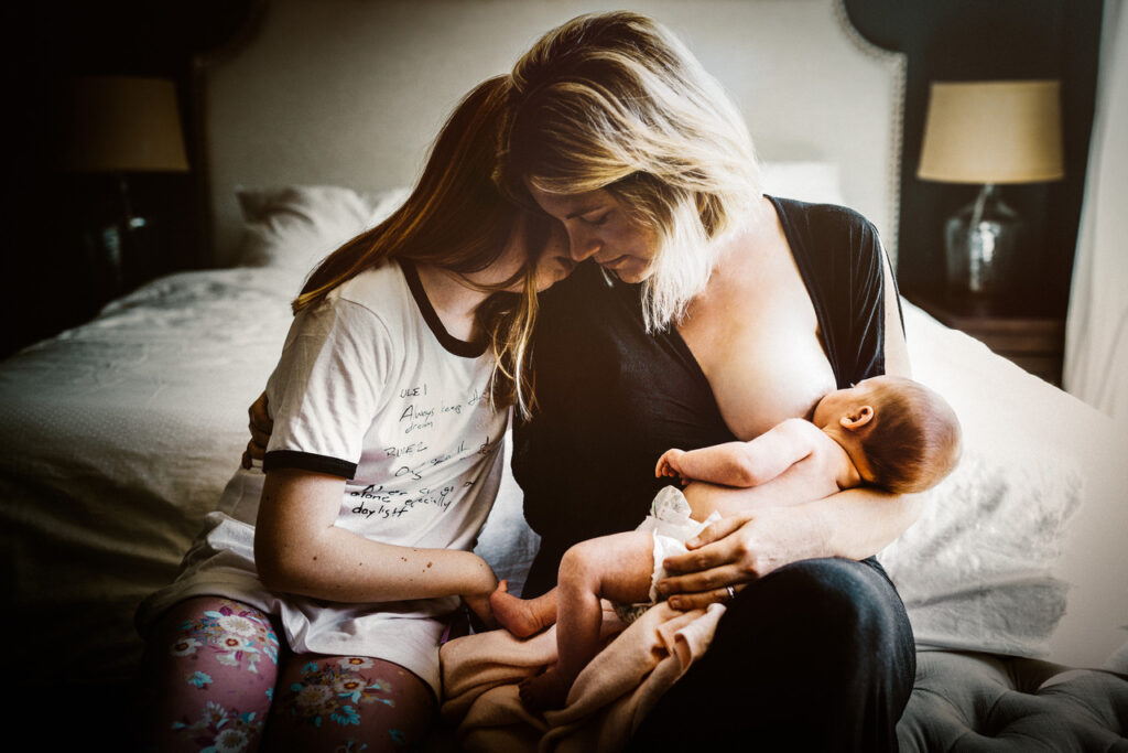 mother and teenage daughter bonding while mom breastfeeds newborn home session bay area alameda
