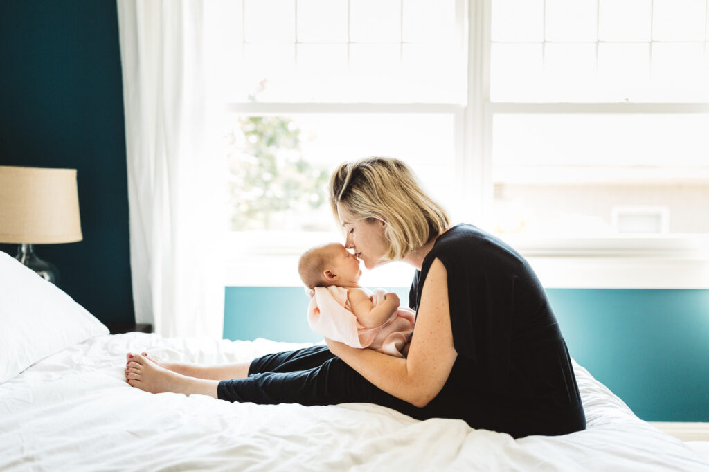 mom tenderly kissing baby daughter newborn home session bay area alameda