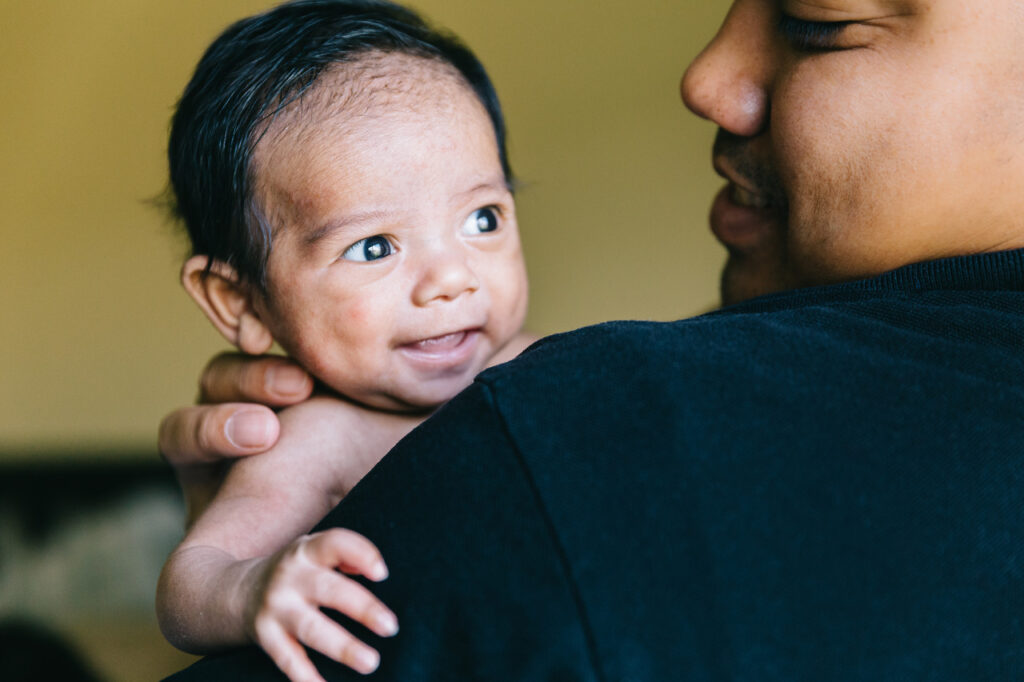 baby boy with cute expression with dad holding him home newborn session sf bay area