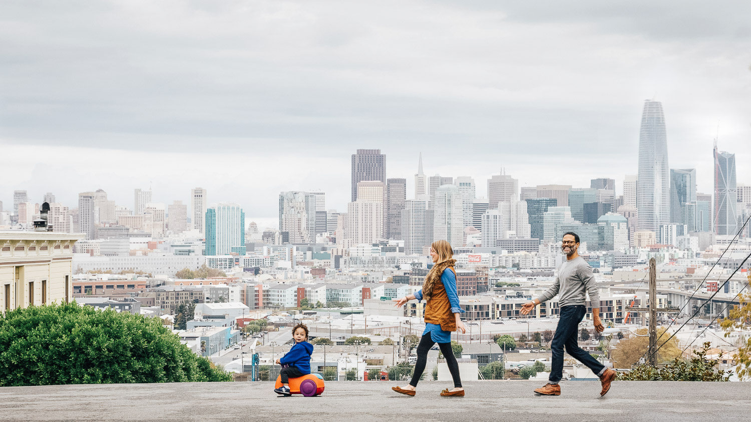 mother, father, and son walking with panoramic views of downtown san francisco