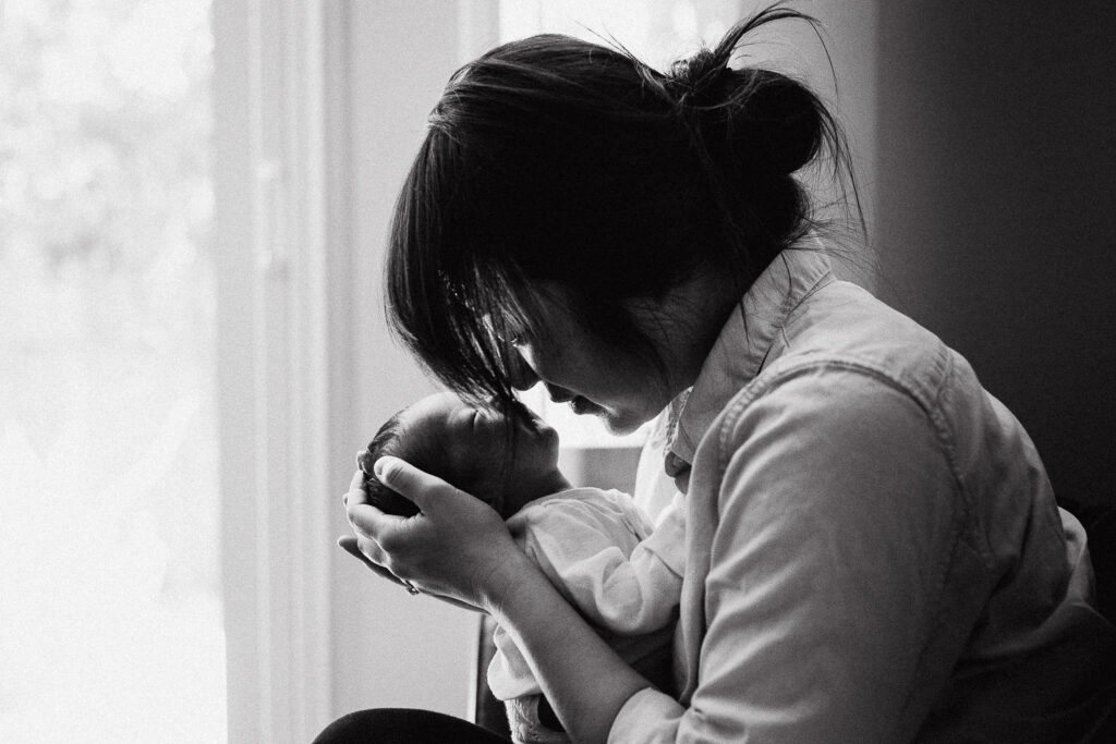 black and white image of mother tenderly holding newborn baby girl