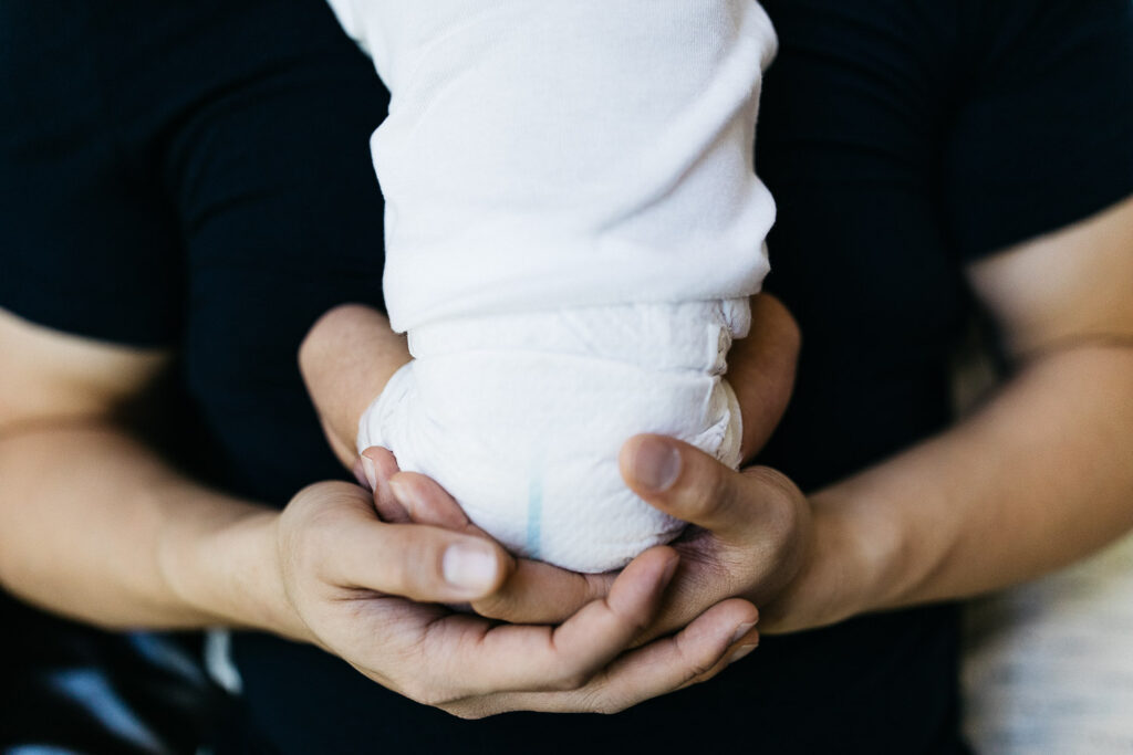 father's hands holding little baby newborn girl