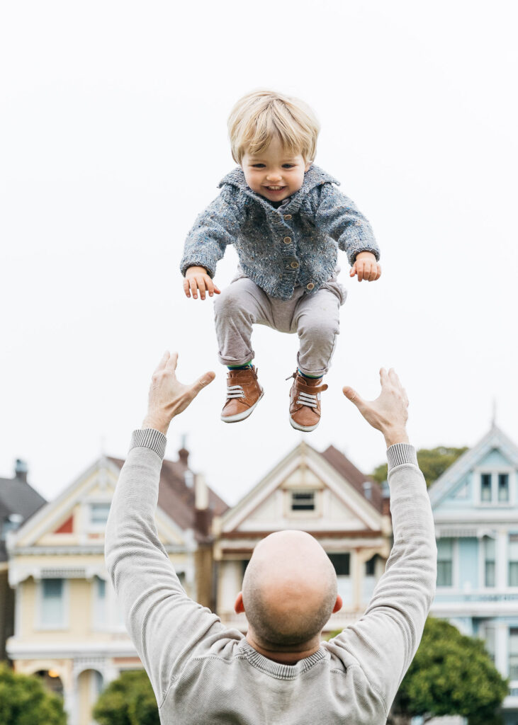 best-san-francisco-bay-area-family-photographer-carmen-dunham-photography-and-filmsIMG_4872 father throwing son in the air at alamo square with painted ladies family session