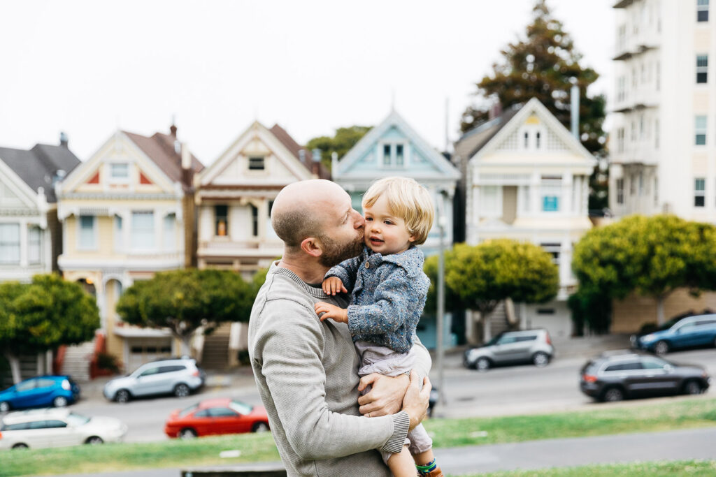 san-francisco-bay-area-family-photographer-carmen-dunham-photography-and-filmsIMG_4873 sweet moment with dad kissing son in alamo square park with famous painted ladies in background