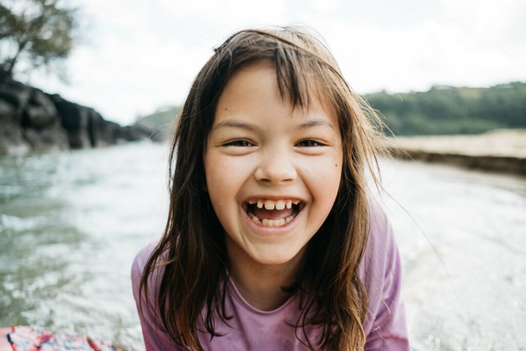 girl laughing while on a boogie board at beach in kauai