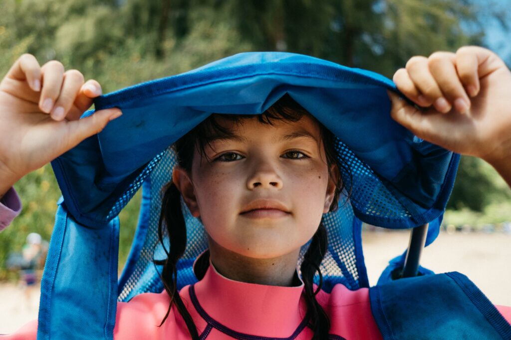 girl wearing a folded chair on her head at kauai beach