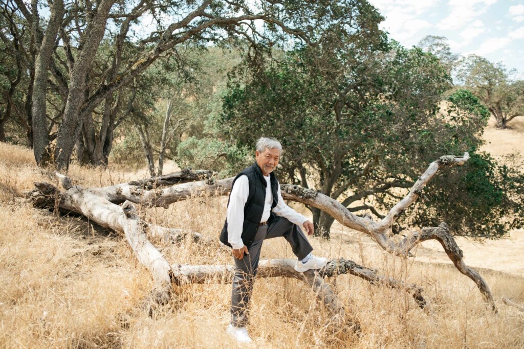 senior asian man posing athletically on a tree branch at borges ranch in walnut creek