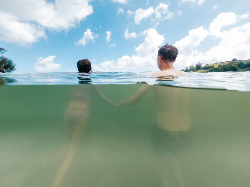 father and daughter holding hands under water at anini beach in kauai