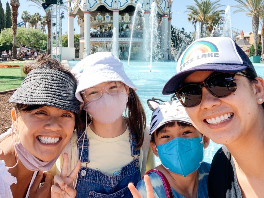 Friends celebrating a birthday in front of fountain and carousel at Great America