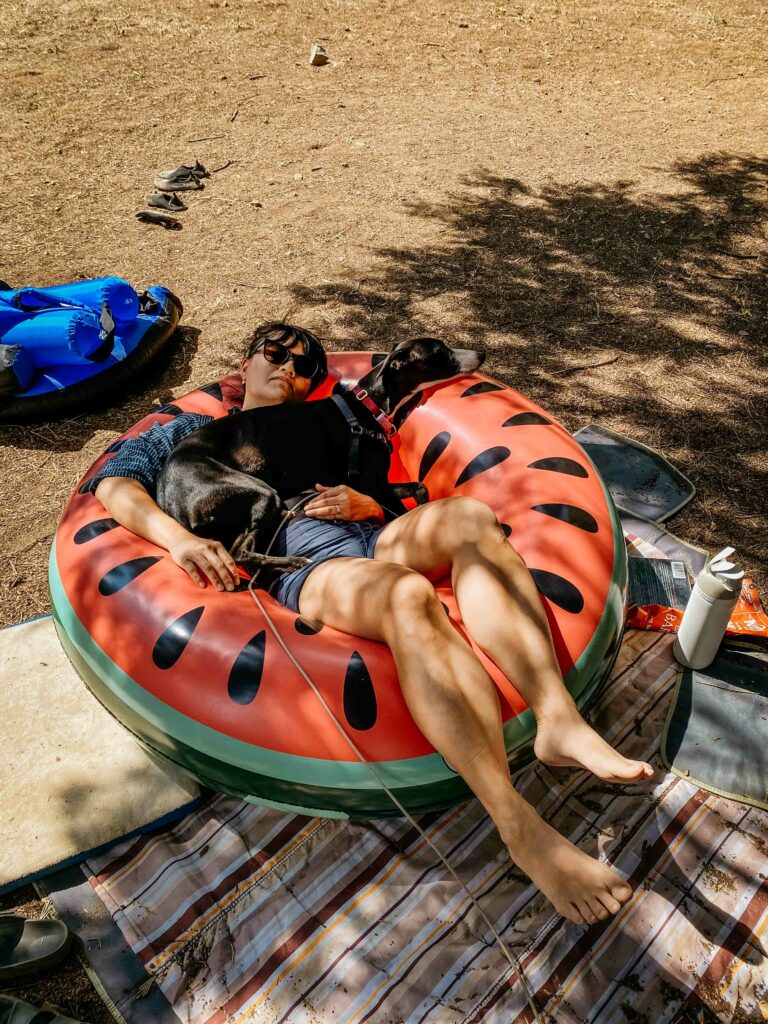 tired mama sleeping with her whippet puppy in an inflatable tube