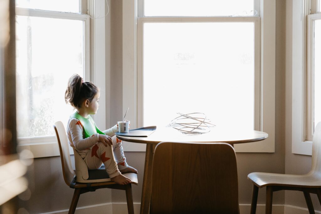 young girl looking outside bay window in the kitchen