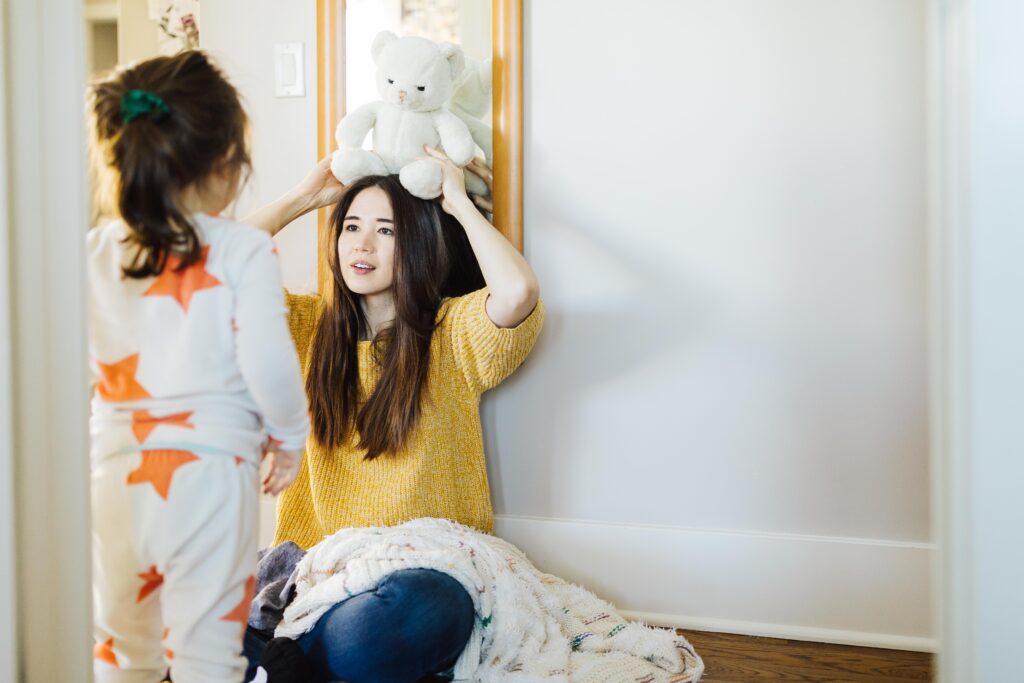 mother and daughter playing with stuffed animals at home