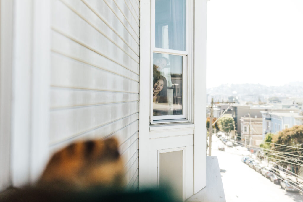 mom and dad saying hello through a window inside san francisco victorian apartment
