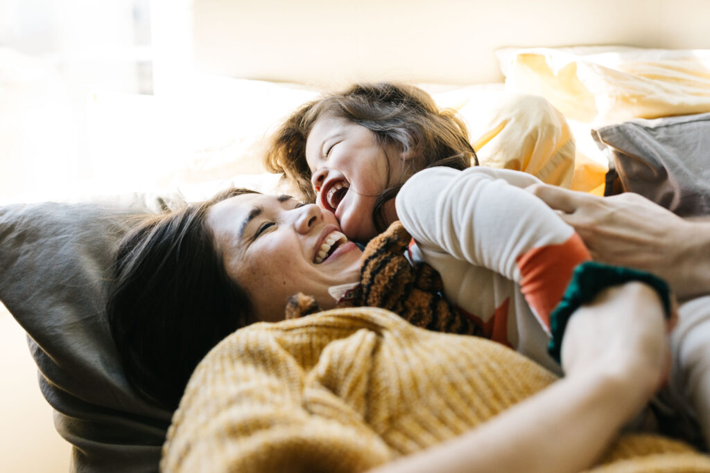 mother and daughter laughing and snuggling in the bed