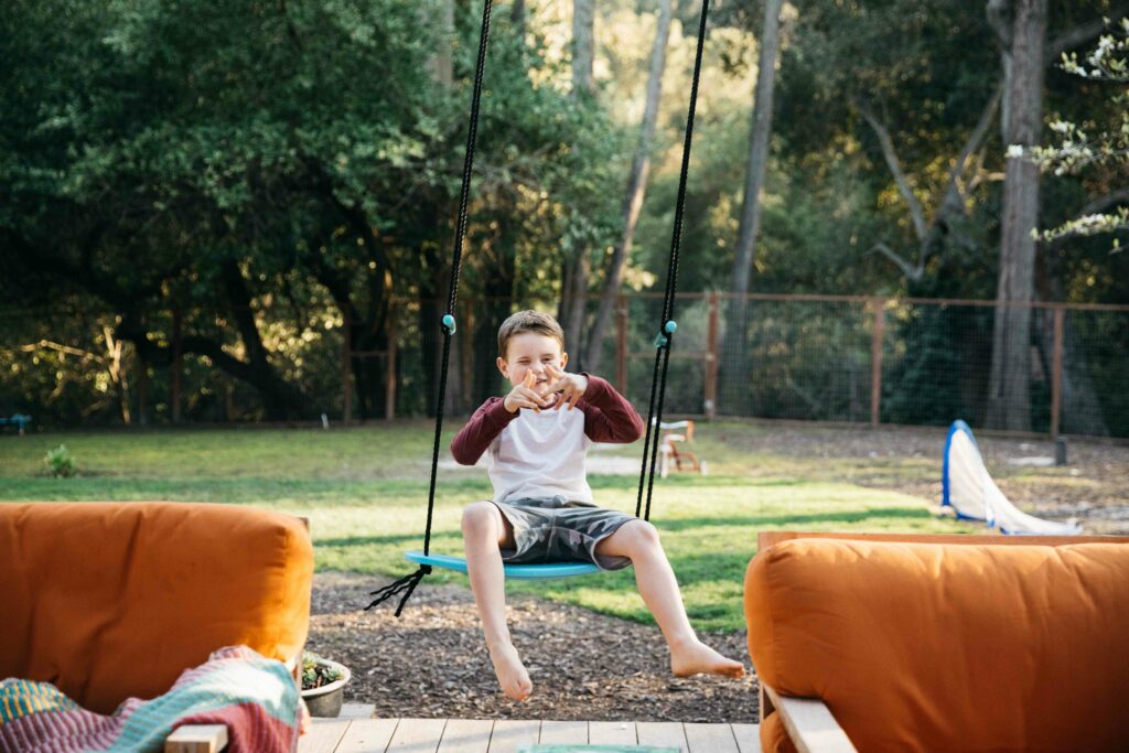 boy being silly on swing in backyard