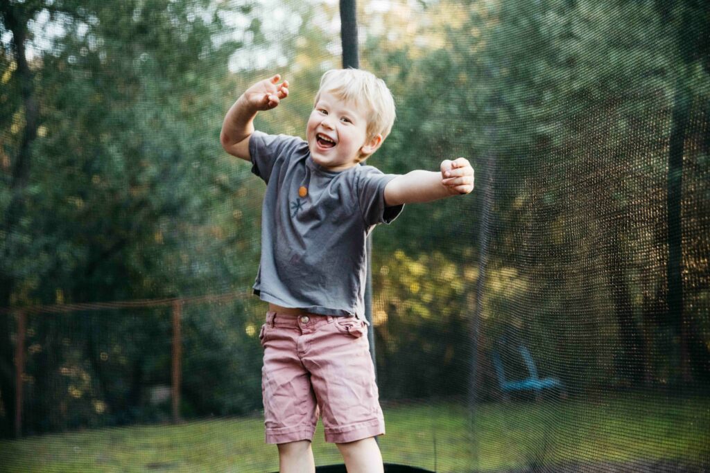 young boy smiling and having a good time on trampoline.