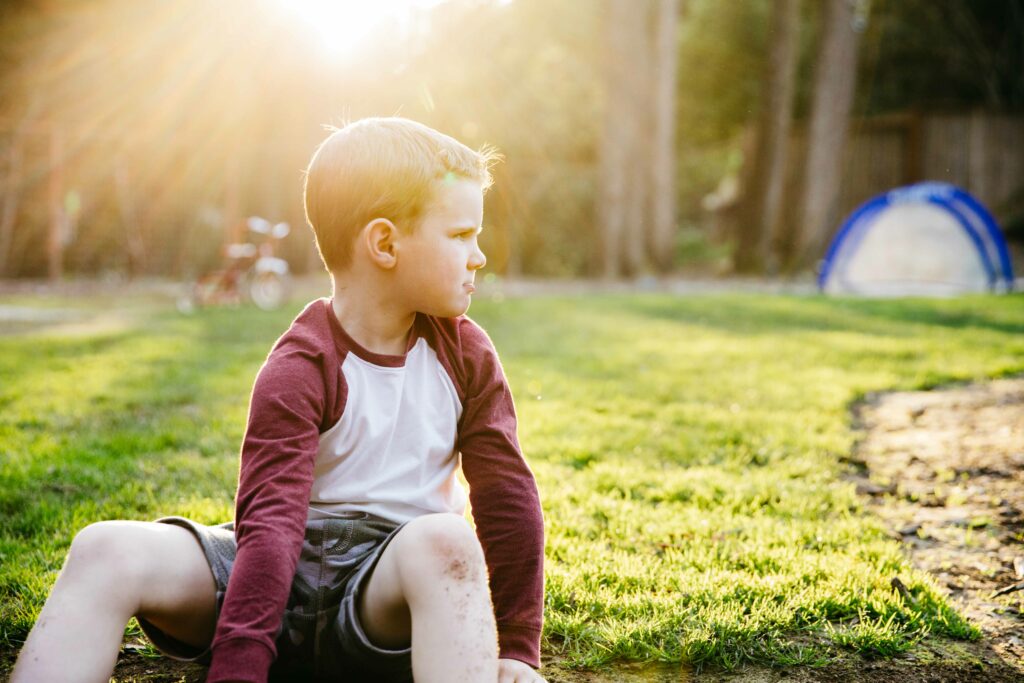 young boy pouting in the backyard