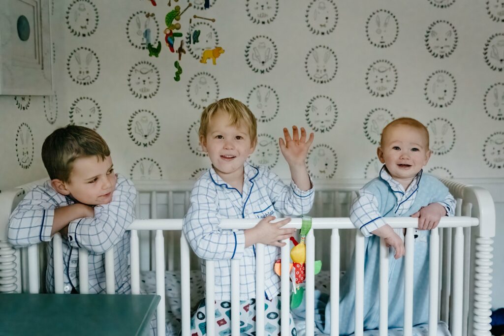 three sibling boys being silly i n the crib.
