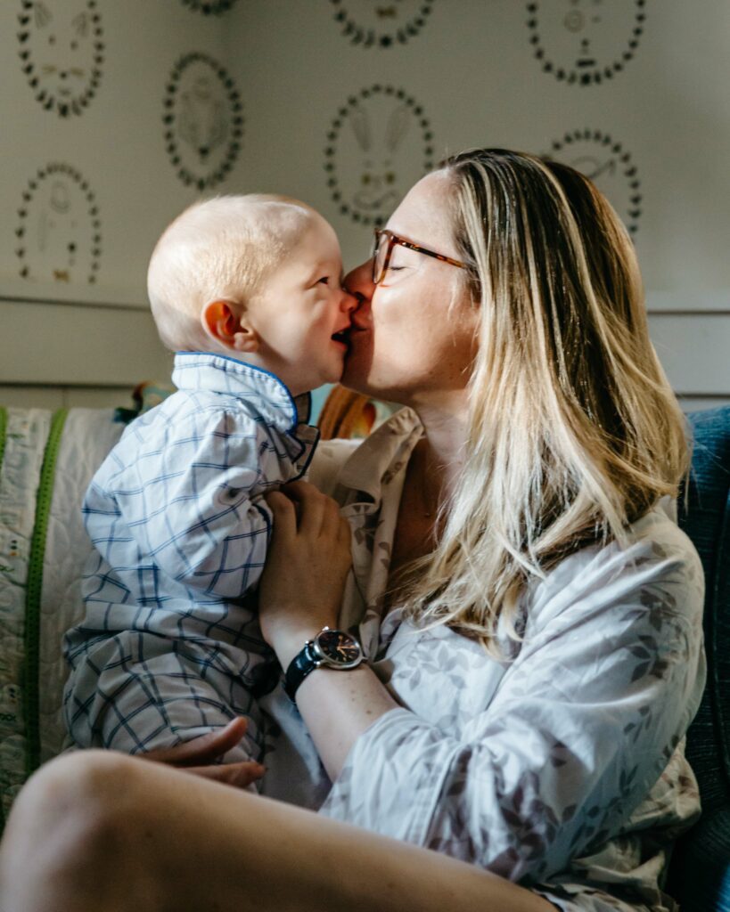 mother kissing baby in the nursery.