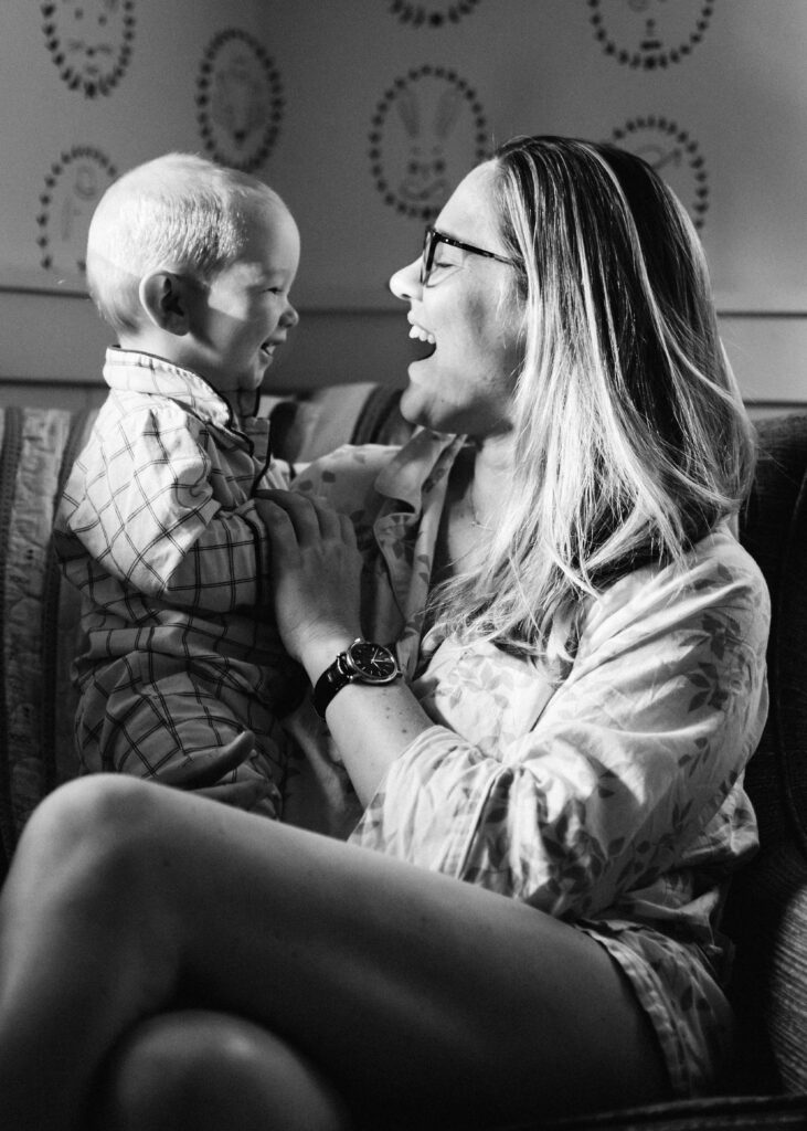 black and white photo of baby laughing with mom in rocker.