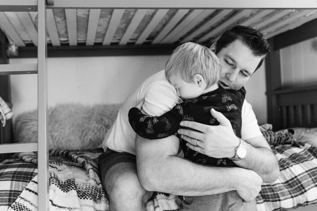 black and white photo of dad and son hugging on the bunk bed.