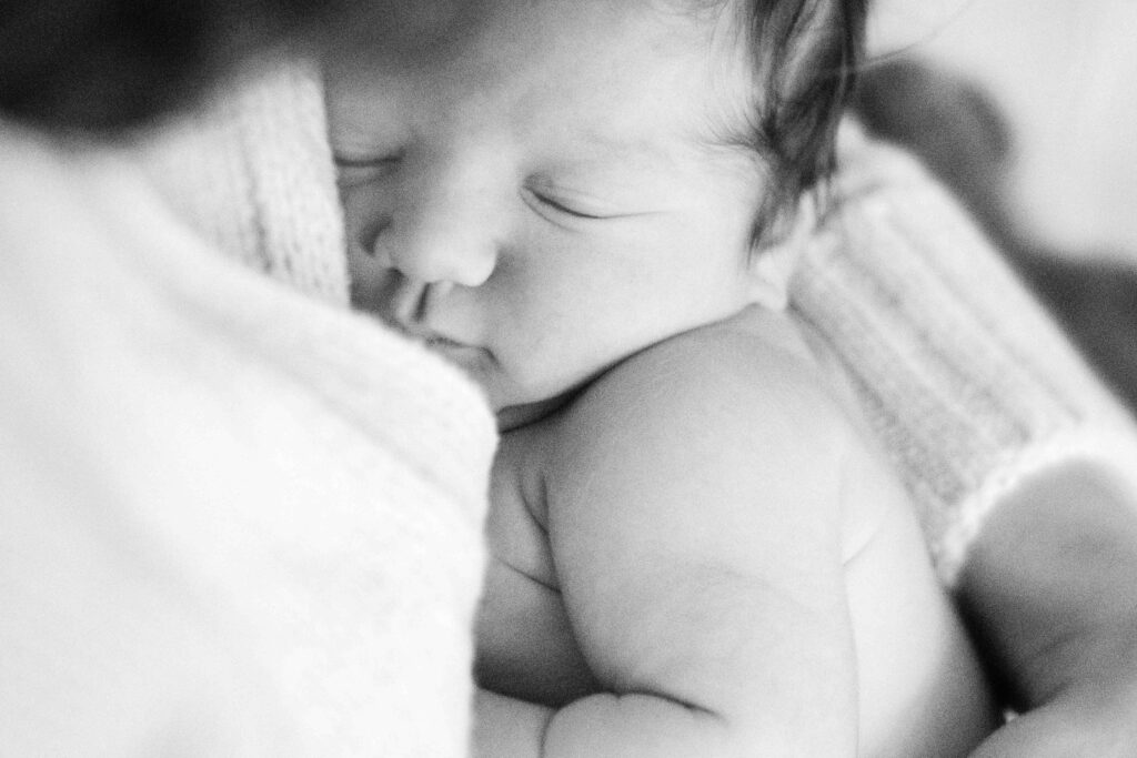 black and white photo of newborn sleeping in mother's arms