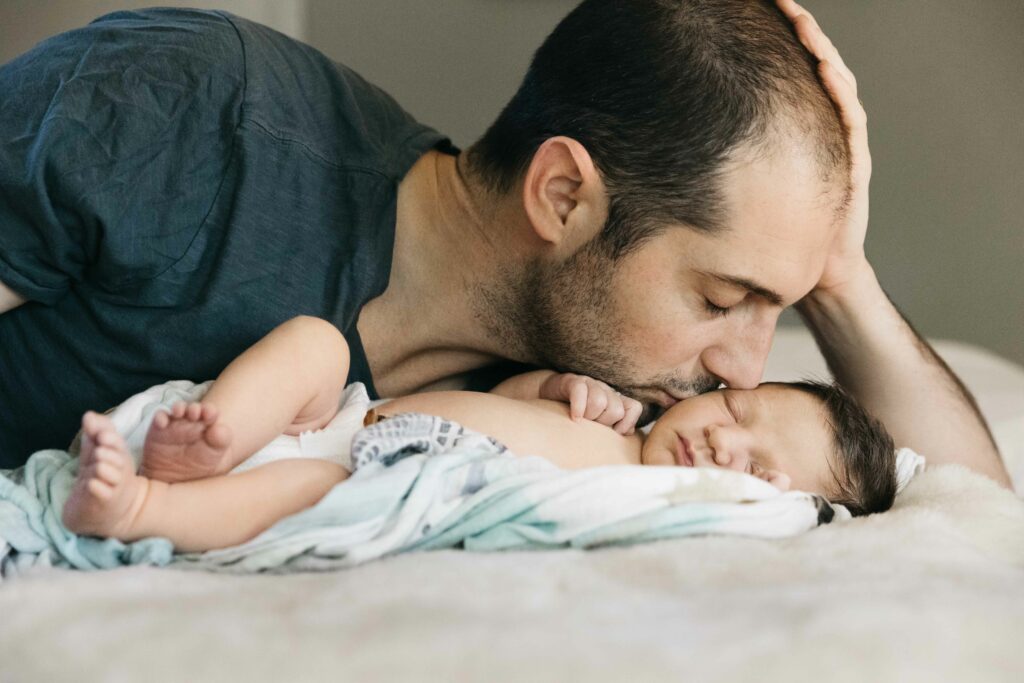 father kissing newborn son in the bed