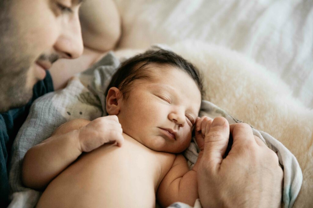 father admiring newborn son in the bed while he sleeps
