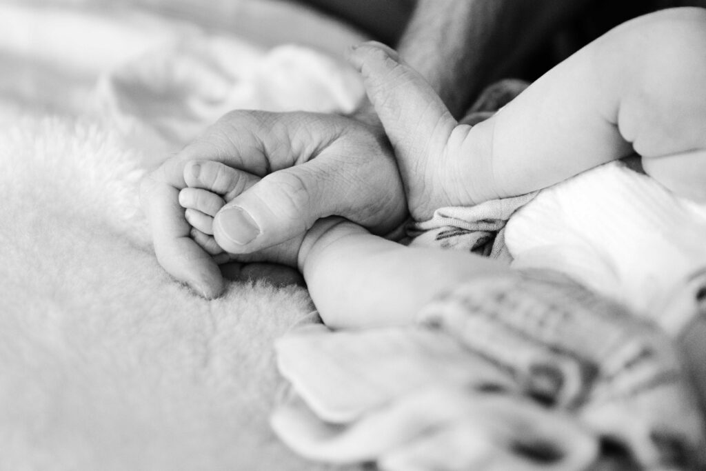 black and white photo of father holding his newborn's toes