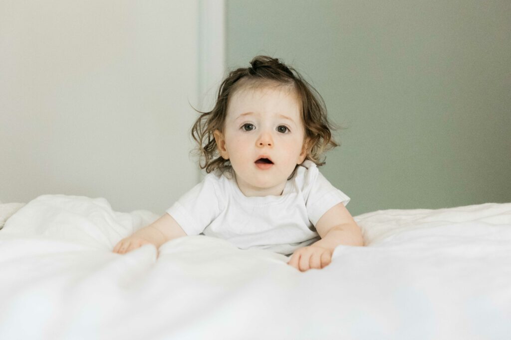toddler girl hanging from mom's bed