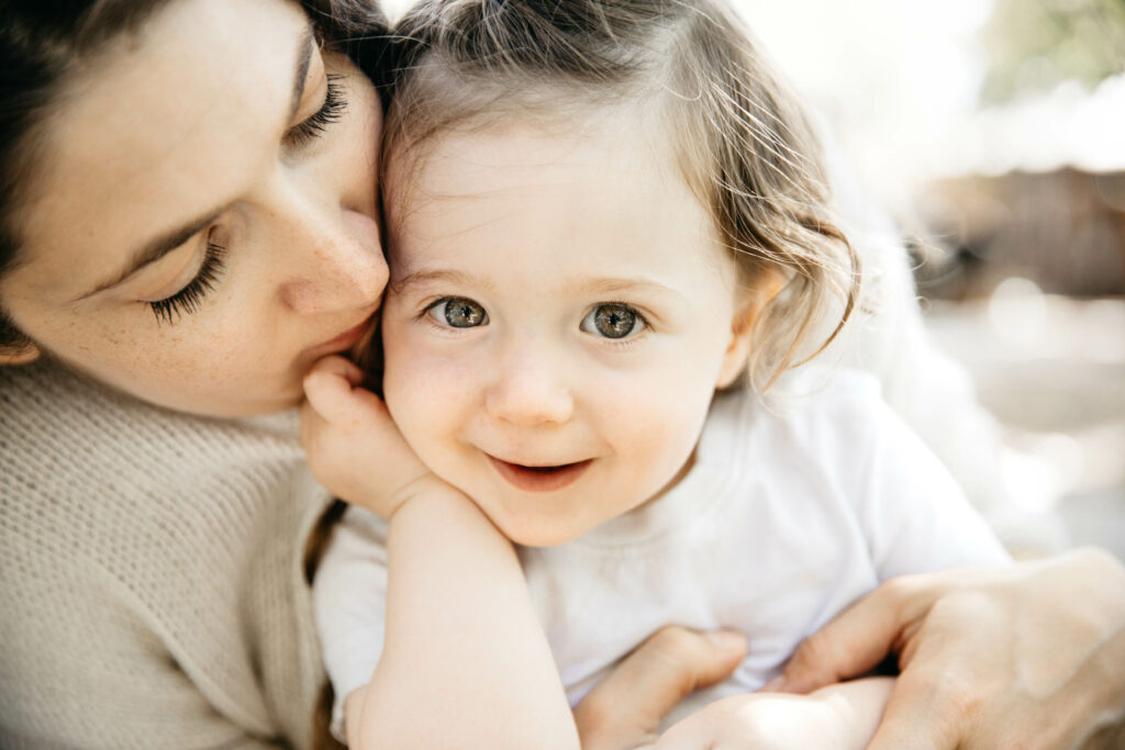 mom and daughter snuggling together in the backyard during newborn session