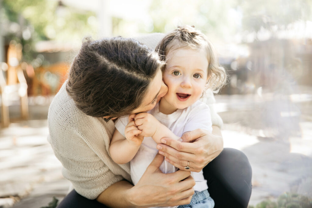 mom and young daughter snuggling in the backyard