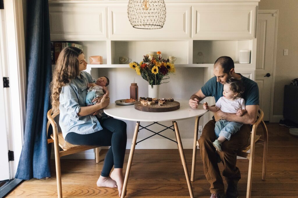 family of four having breakfast with new baby at their kitchen table